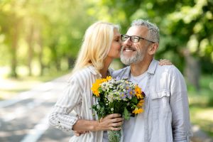 Elderly couple holding a bouquet together, smiling warmly.